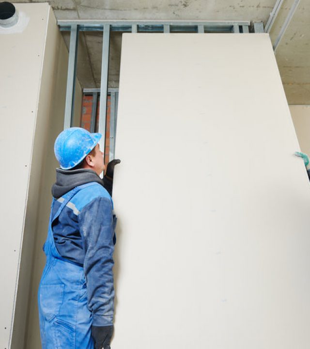 cheerful plasterboard workers team at a indoors wall insulation works